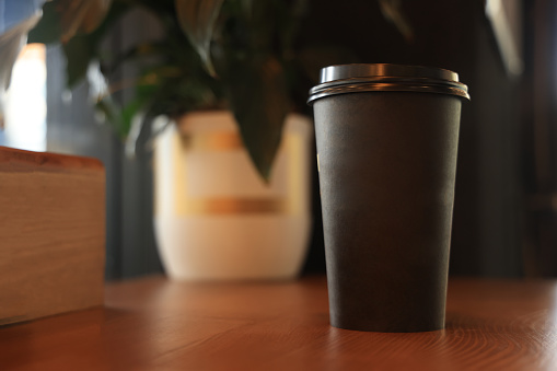 Coffee paper cup on wood table in coffee shop.