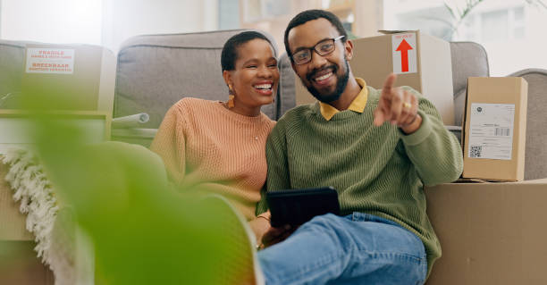 istock African couple, pointing and new home with tablet, boxes and thinking with discussion, decision and choice. Black woman, man and floor for planning, moving or chat for real estate, property or house 1847136582