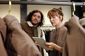 Young female shop assistant using tablet during consultation of male client