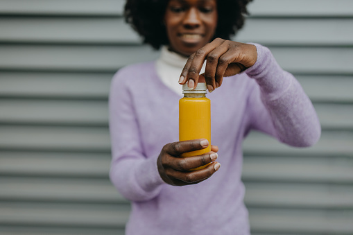 Woman holding plastic container with orange juice