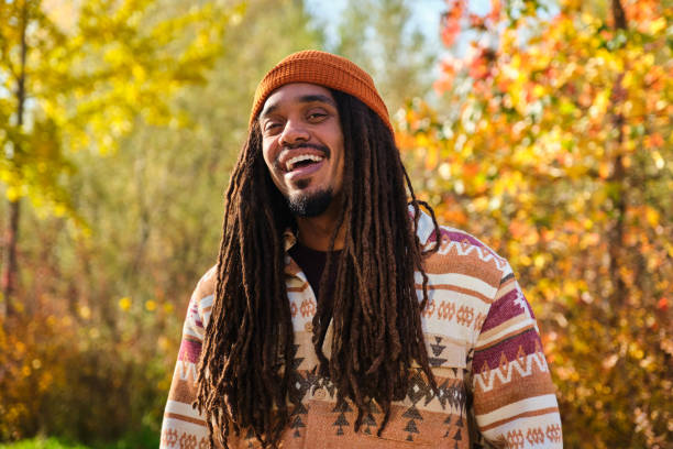 African young man with dreadlocks laughing and looking at camera in fall.