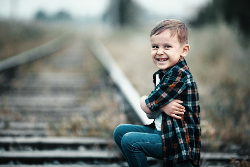Lonely boy sits on railroad tracks. Mischievous man ran away from home. Bad boy