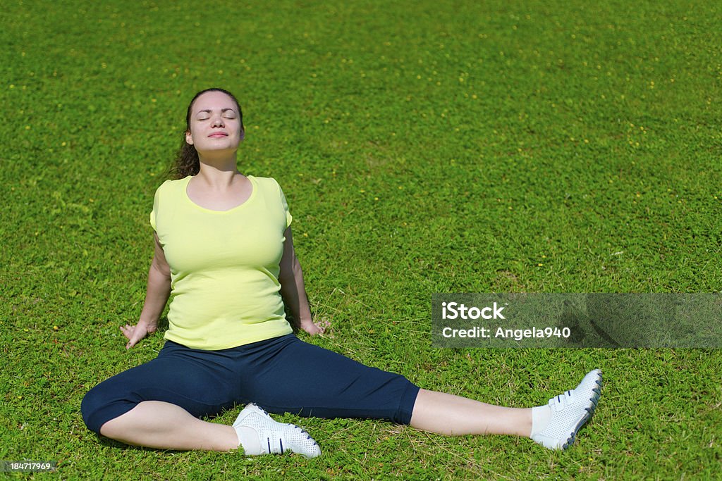 Szczęśliwa młoda kobieta robi ćwiczenia na zielonej trawie - Zbiór zdjęć royalty-free (20-29 lat)
