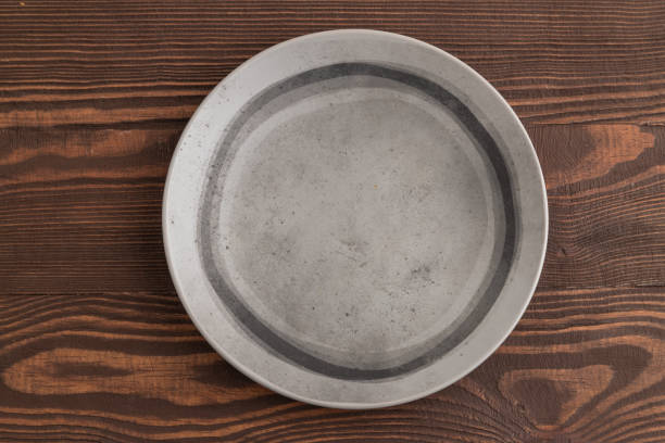 istock Empty gray ceramic plate on brown wooden background. Top view, copy space 1847197965