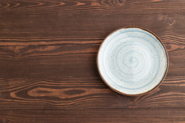 Empty blue ceramic plate on brown wooden background. Top view, copy space, flat lay.