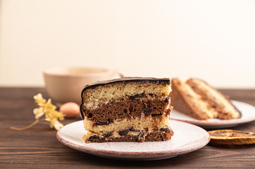 Chocolate biscuit cake with caramel cream, cup of coffee on brown wooden background. side view, close up, selective focus, copy space