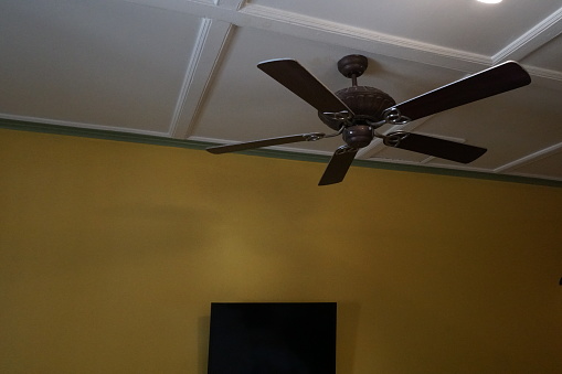 Stock photo showing a non moving three blade, ceiling fan viewed against a white ceiling as seen from below.