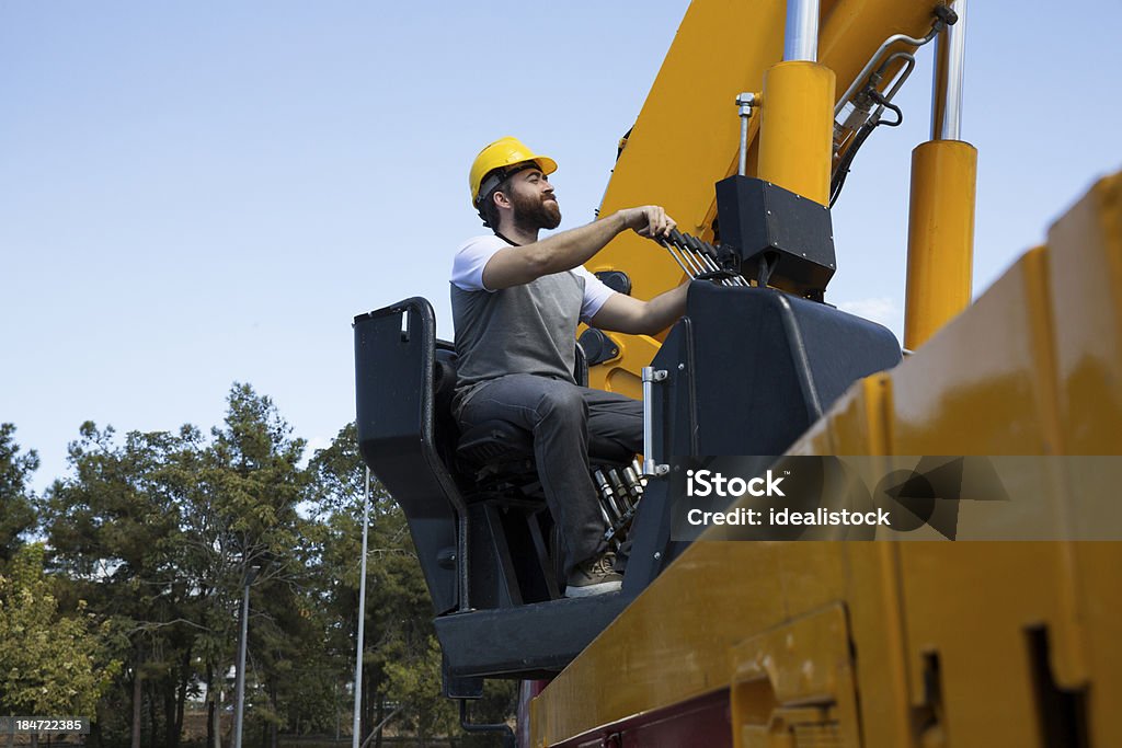 Construction Worker Construction worker sitting on the crane seat and controlling the direction gears. Adult Stock Photo
