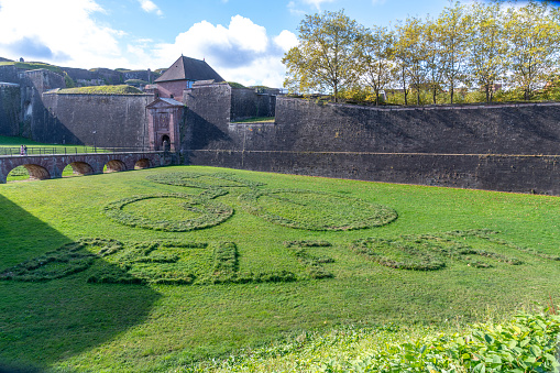 Lawn in front of the citadel in Belfort on which the word Belfort and a cyclist symbol have been mown into the lawn. The citadel can be seen in the background.