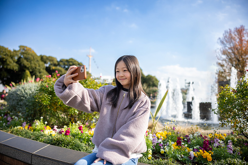 Teenage girl taking selfie picture in public park