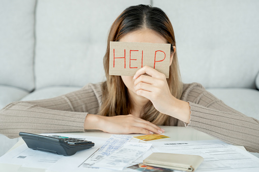 Stressed and headache asian woman with large bills or invoices no money to pay to expenses and credit card debt. shortage, Financial problems, mortgage, loan, bankruptcy, bankrupt, poor, empty wallet