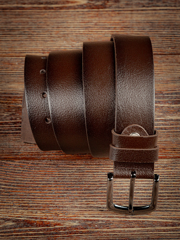 Variety of modern leather belts on wooden table.