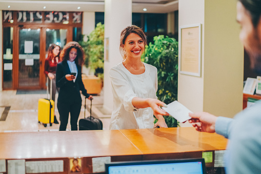 Hotel receptionist giving card key to young tourist woman