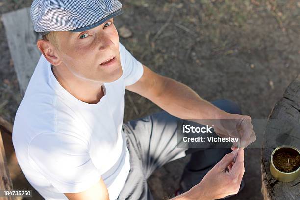 Photo libre de droit de Homme Caucasien Rouler Une Cigarette Dans Le Parc banque d'images et plus d'images libres de droit de Abus de substances - Abus de substances, Adulte, Assis