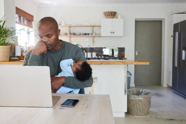 istock Tired dad holding his baby son while working from home on a laptop 1847371725