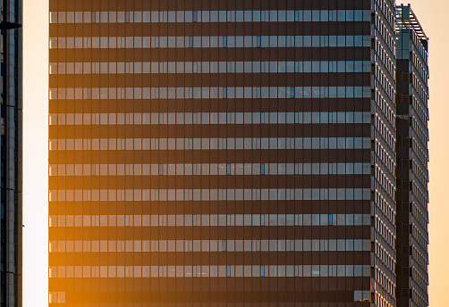 Modern commercial skyscraper facade in dusk light and shadow.