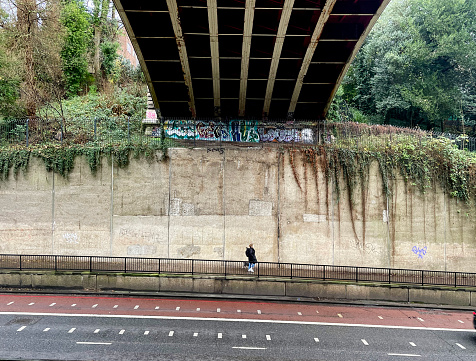 Woman walking her dog down Archway Road (A1) under Archway Bridge in North London (December 2022)