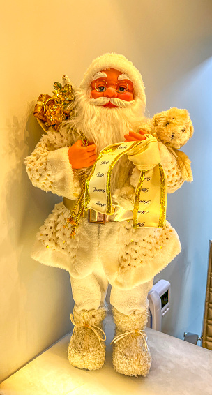Santa Claus toy figure on white shelf on background of white wall.
