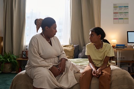 African American mom having serious conversation with her adult daughter while they sitting at home