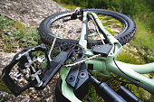 mountain bike lies on the mountainside. A tired bicycle lies on a stone in the grass on the side of the road