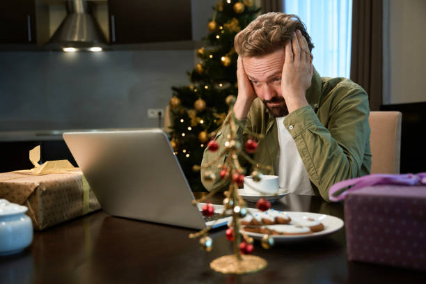 istock Man using laptop working remotely at Christmas Eve being tired and overworked 1847406791