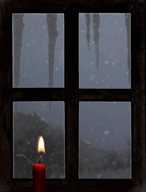 istock View through an old wooden window with a candle in winter 1847439580