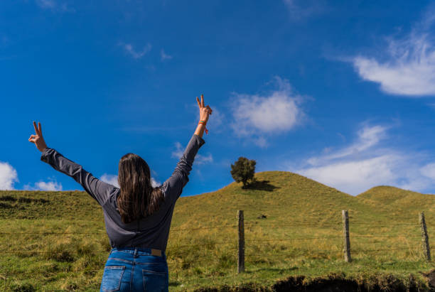 young woman at the edge of a mountain with her back turned and her arms open wide young woman at the edge of a mountain with her back turned and her arms open wide escapada urbana stock pictures, royalty-free photos & images