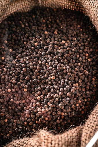 Close-up of black peppercorns packaged in a burlap bag.