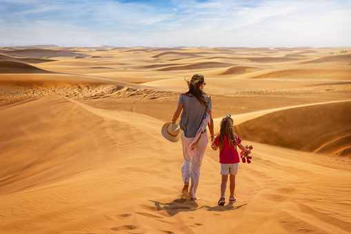 A mother and daughter exploring the sandy desert dunes near Dubai, Middle East