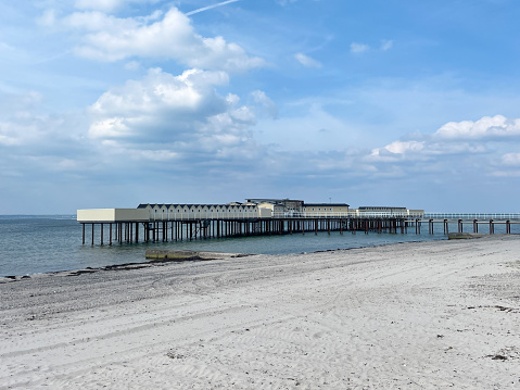 Public cold water swimming bath house in Helsingborg, where people go for cold water dips, have a sauna and relax. The building was destroyed in a storm and rebuilt in 2015. The weather is sunny. The view is looking across the beach.