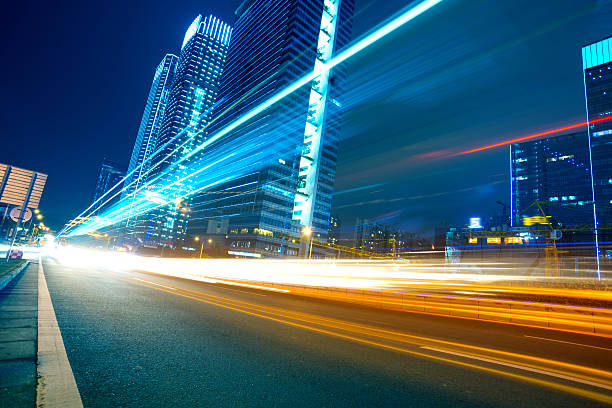 Light trails on a city street the light trails on the modern building fast lane stock pictures, royalty-free photos & images