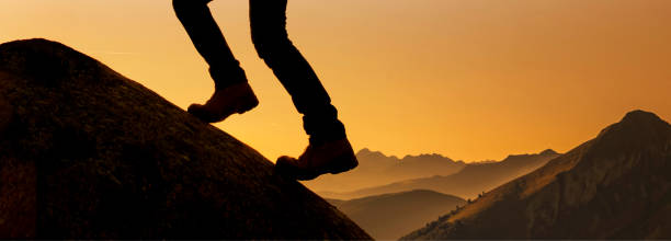 istock Legs with mountain boots on a mountain peak against the light 1847500189