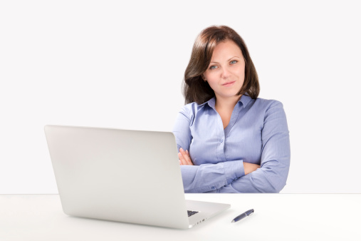 Businesswoman is sitting in front of a modern laptop and looking at the camera, business concept