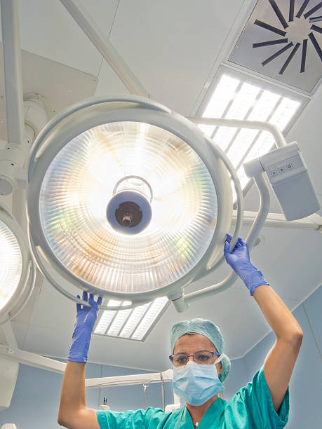 nurse places  surgical lamp on the operating table stock photo