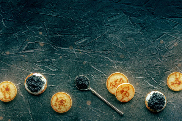 Blinis with black caviar and cream cheese, top shot on black
