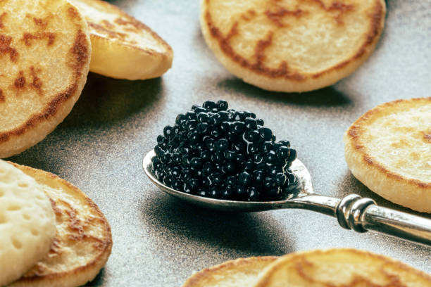 Silver spoon with caviar closeup with blinis, an elegant festive appetizer