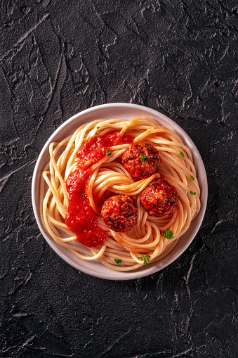 Meatballs. Beef meat balls, shot from above with spaghetti pasta, parsley, and tomato sauce, on a black background