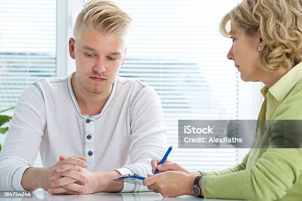 A Doctor Taking Notes With A Young Male Patient Stock Photo - Download Image Now - Adolescence, Adult, Advice