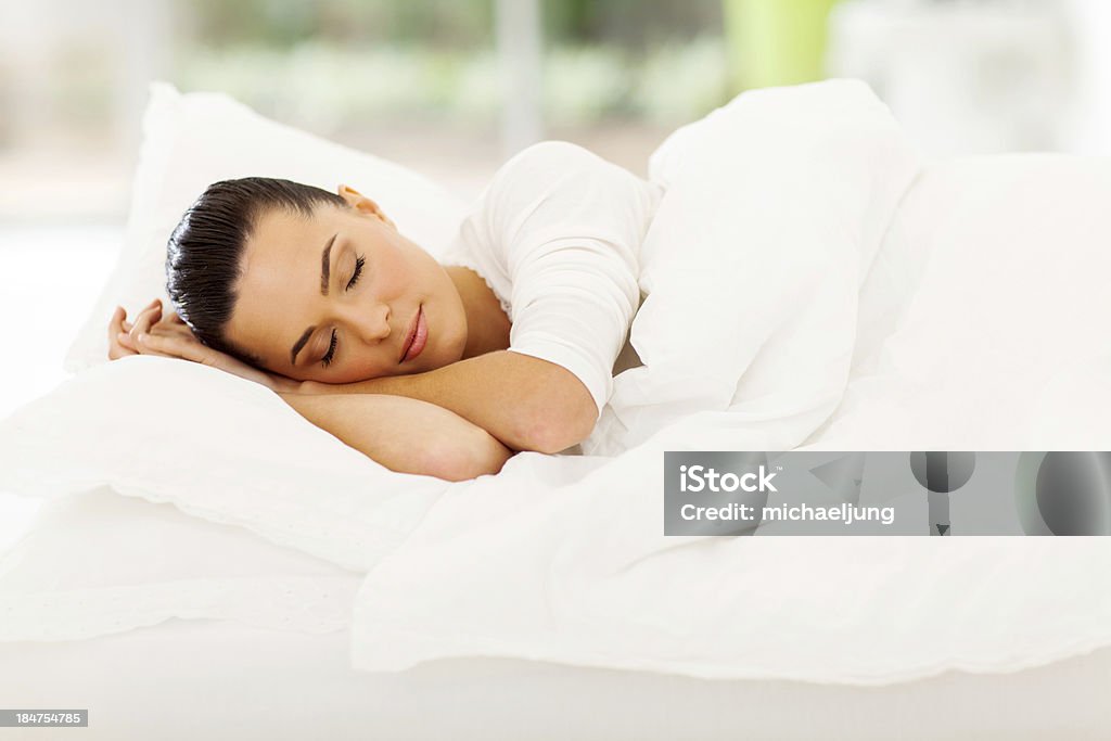 Pretty young woman sleeping in fluffy bed with white sheets cute woman sleeping in bed Adult Stock Photo