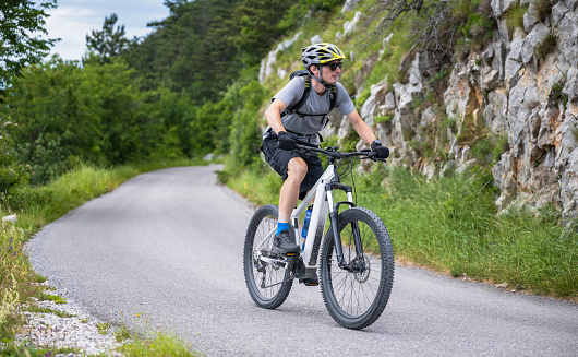 Male sportler riding electric mountain bike on the road. Healthy lifestyle concept.