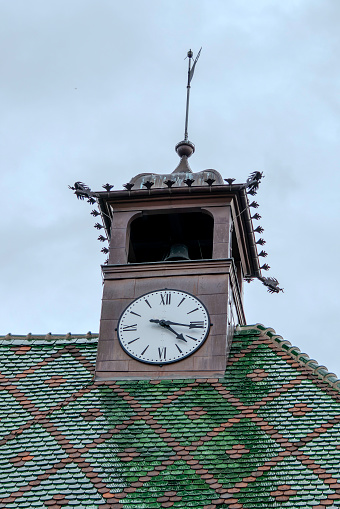 Colmar, France, July 23, 2023. clock on a tiled roof colored in green