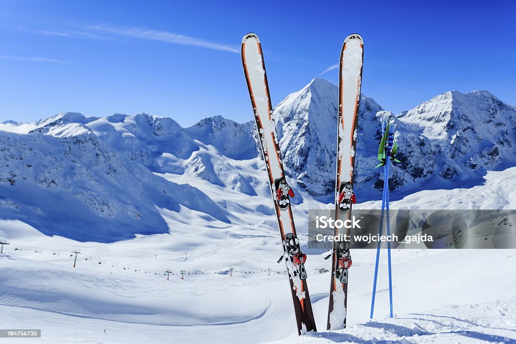 Image of ski gear stuck in snow against mountain backdrop Ski run in Italian Alps Dolomites Stock Photo
