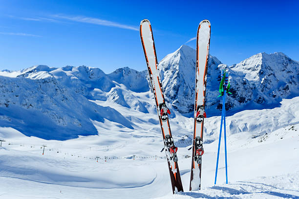 Image of ski gear stuck in snow against mountain backdrop stock photo