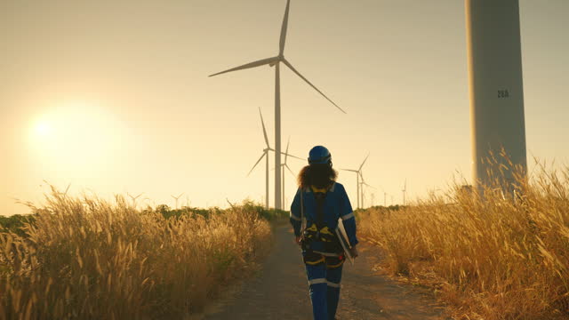 black woman Engineer walking in wind turbine farm with Solar panel in the evening, Green power technology concept