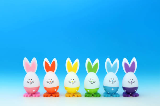 Easter bunny eggs decorated in rainbow spectrum colors on gradient blue white background. Minimal cute fun composition with Lgbt trans theme for the holiday season.