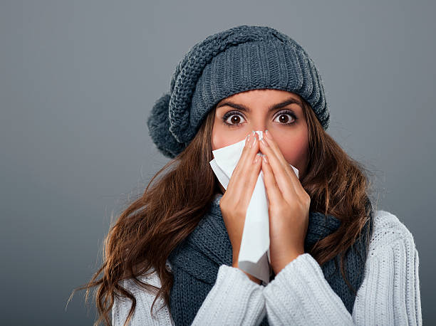istock Young woman wearing warm hat sneezing 184759952