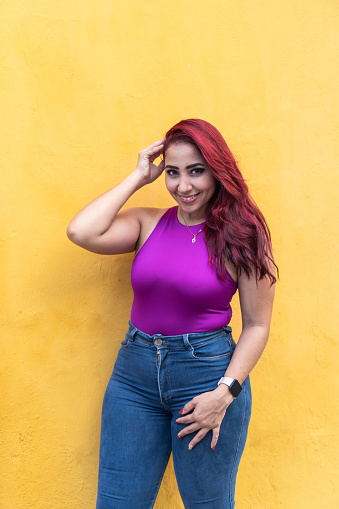 Vivacious woman with vibrant red hair posing with a hand on her hip