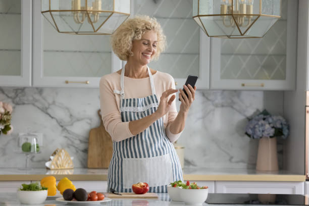istock Cheerful mature smartphone user lady consulting cook blog on Internet 1847656302