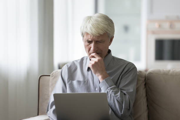 istock Frowning worried retired old man using laptop computer at home 1847656329