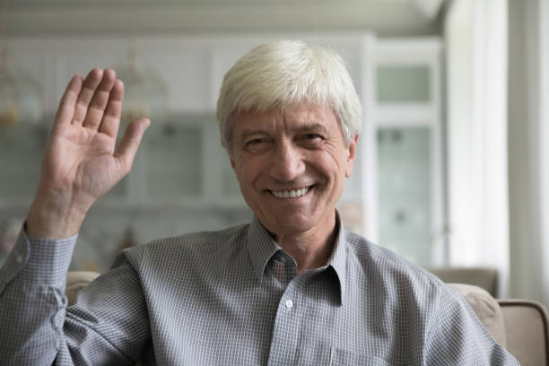 istock Happy senior man smiling at camera, waving hand hello 1847656382
